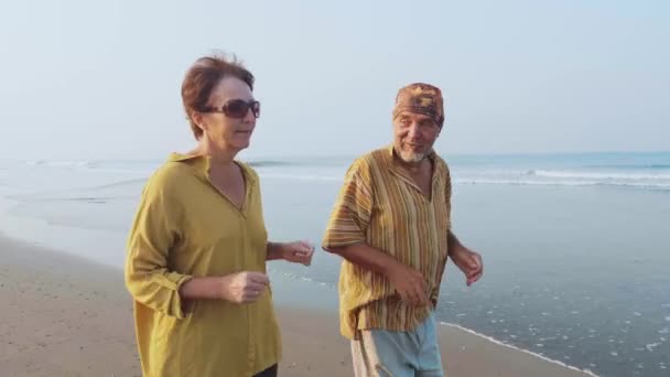 Casal sénior ativo correndo na praia de areia ao nascer do sol — Vídeo de Stock