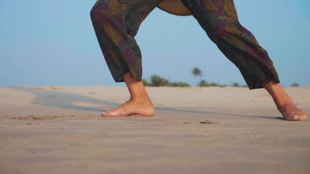 Pieds de femme âgée active pratiquant le tai chi gymnastique sur une plage de sable fin . — Video