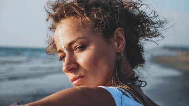 Portrait of young pretty woman standing on the beach and  looking on the sea