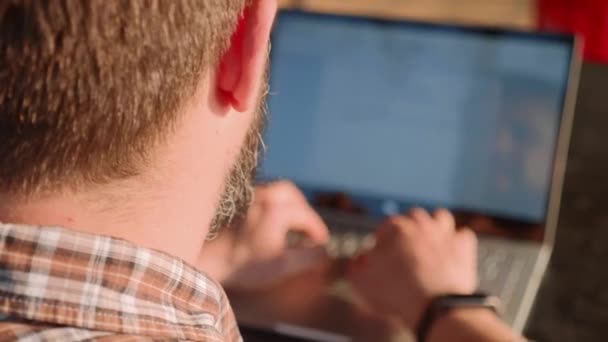 Красивый бородатый мужчина печатает на открытом ноутбуке — стоковое видео