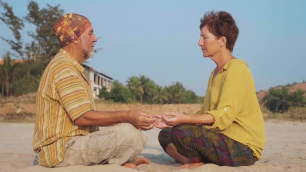 Casal sênior senta e meditando juntos na praia de areia — Vídeo de Stock