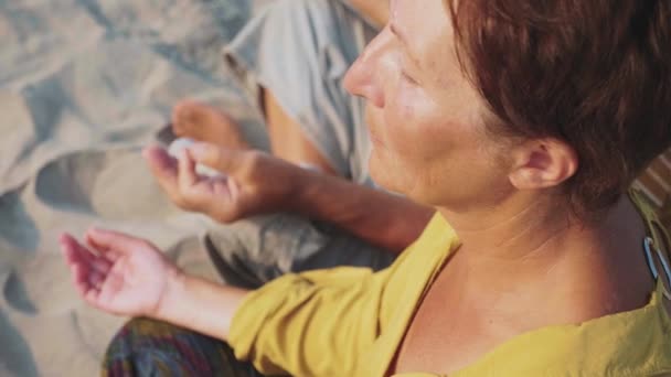 Skörd av ledande par sitter och mediterar tillsammans på sandstrand — Stockvideo