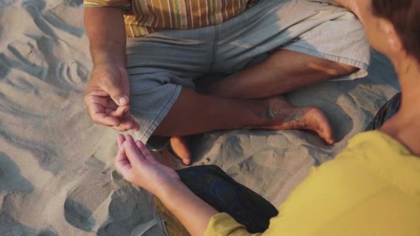 Oogst van senior paar zit en samen mediteren op zandstrand — Stockvideo