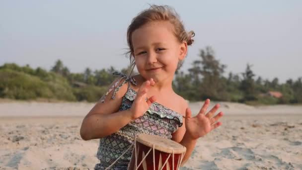 Roztomilá holčička dítě, hrát na bicí na písečné pláži. — Stock video