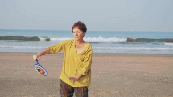 Старшая женщина практикует воздушный шар тай-чи на пляже — стоковое видео
