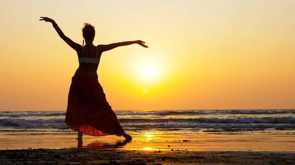 Silhueta de menina dançando na praia ao pôr do sol — Fotografia de Stock