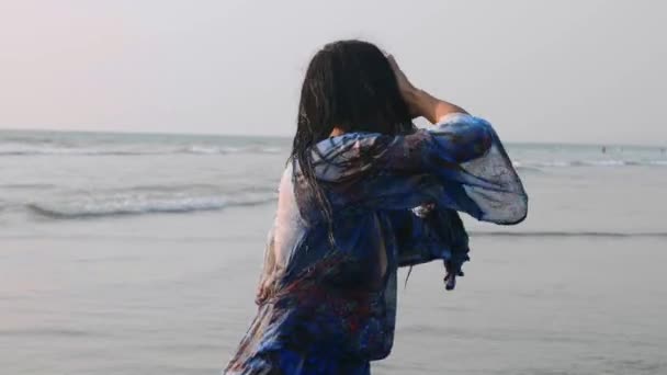 Mulher atraente em vestido azul gira a cabeça com o cabelo molhado enquanto ela dança — Vídeo de Stock