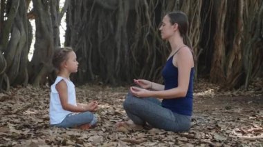 Genç anne birlikte Hint inciri ağacı altında meditasyon ile küçük çocuk kız