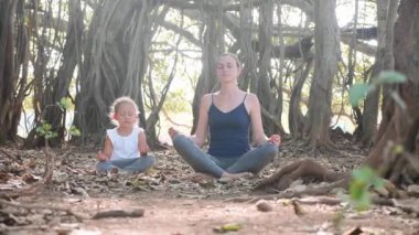 Genç anne birlikte Hint inciri ağacı altında meditasyon ile küçük çocuk kız