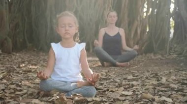 Genç anne birlikte Hint inciri ağacı altında meditasyon ile küçük çocuk kız