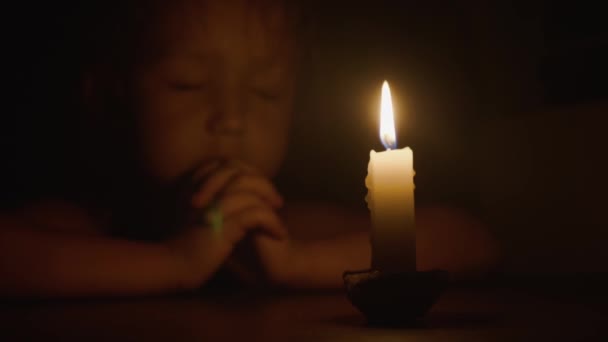 可爱的小女孩在黑暗中祈祷闭着眼睛 前燃烧的蜡烛 特写镜头 — 图库视频影像