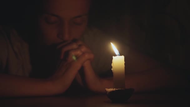 Mujer joven está rezando un frente de vela encendida, primer plano — Vídeo de stock