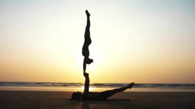 Sportif kaç ortakla birlikte kum plajındaki Acro yoga uygulamak uygun.