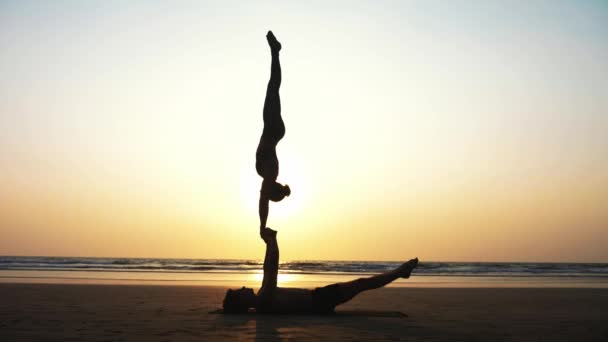 Подходящая спортивная пара практикует акро-йогу с партнером вместе на песчаном пляже . — стоковое видео