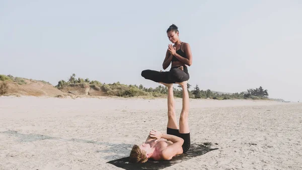 Fit sportovní pár cvičení acro jógy s partnerem společně na písečné pláži. — Stock fotografie