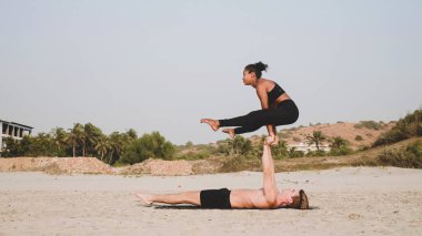 Sportif kaç ortakla birlikte kum plajındaki Acro yoga uygulamak uygun.