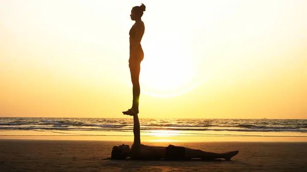 Fit sportovní pár cvičení acro jógy s partnerem společně na písečné pláži. — Stock fotografie