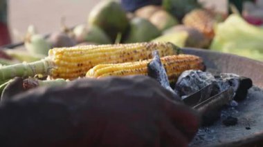Tatlı mısır koçanı bir kömür ve sokak satıcıları çevirerek kavurma.