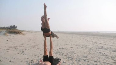 Sportif kaç ortakla birlikte kum plajındaki Acro yoga uygulamak uygun.