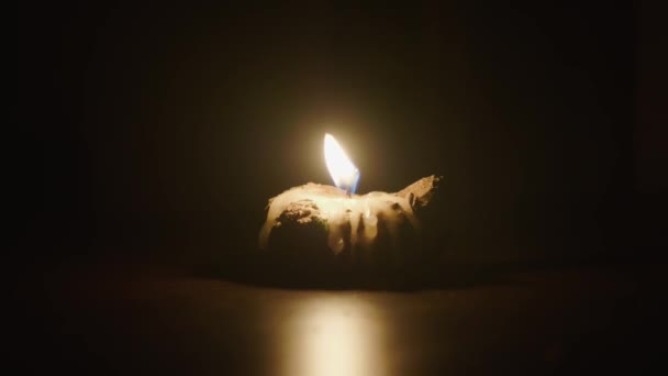 Burning candle in candlestick on the table in dark room — Stock Video