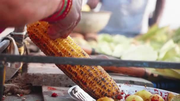 Street vendor is rubbing a roasted sweet corn cob with lemon and spices. — Stock Video