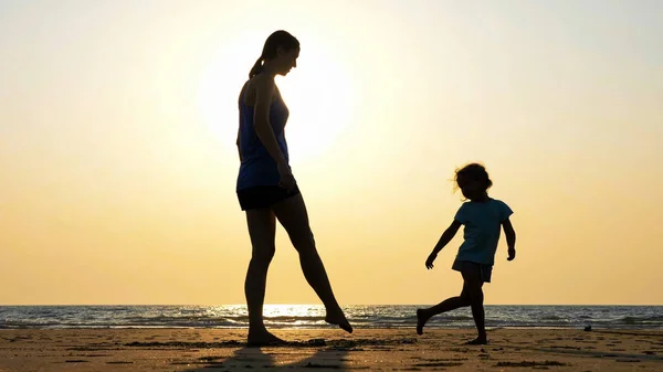 Silueta de madre e hija divirtiéndose en la playa — Foto de Stock