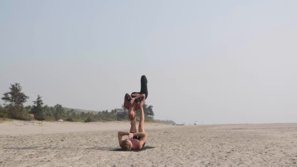 砂浜のビーチで一緒にパートナーとアクロ ヨガ フィットのスポーティなカップル. — ストック動画
