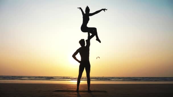 Fit sporty couple practicing acro yoga with partner together on the sandy beach. — Stock Video