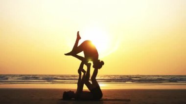 Sportif kaç ortakla birlikte kum plajındaki Acro yoga uygulamak uygun.