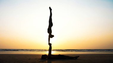 Sportif kaç ortakla birlikte kum plajındaki Acro yoga uygulamak uygun.
