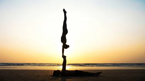 Ajuste pareja deportiva practicando acro yoga con pareja juntos en la playa de arena . — Foto de Stock