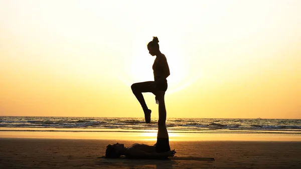 Fit sportovní pár cvičení acro jógy s partnerem společně na písečné pláži. — Stock fotografie