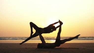 Sportif kaç ortakla birlikte kum plajındaki Acro yoga uygulamak uygun.
