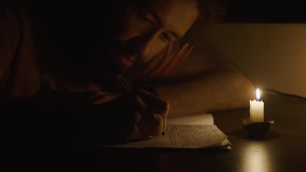 Zbliżenie: człowiek pisania przez pióro w blasku świec o ciemniej Pokój — Wideo stockowe