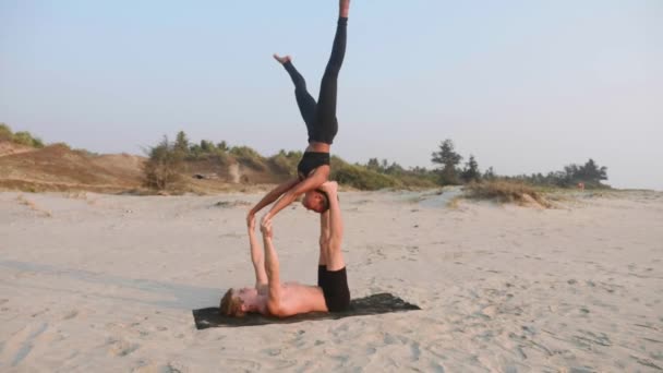 适合运动的夫妇练习阿克罗瑜伽与合作伙伴一起在沙滩上. — 图库视频影像