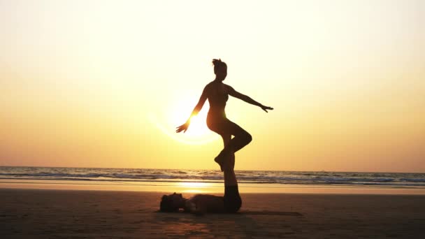 Fit sportieve paar beoefenen van acro yoga met partner samen aan het zandstrand. — Stockvideo