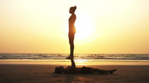 Apto casal desportivo praticando acro ioga com parceiro juntos na praia de areia . — Vídeo de Stock