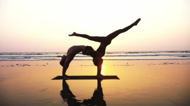 Подходящая спортивная пара практикует акро-йогу с партнером вместе на песчаном пляже . — стоковое видео