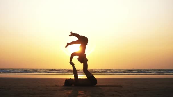 Ajuste pareja deportiva practicando acro yoga con pareja juntos en la playa de arena . — Vídeos de Stock