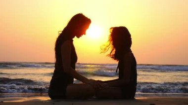 Anne ve kızı okyanusta güzel günbatımında birlikte meditasyon.