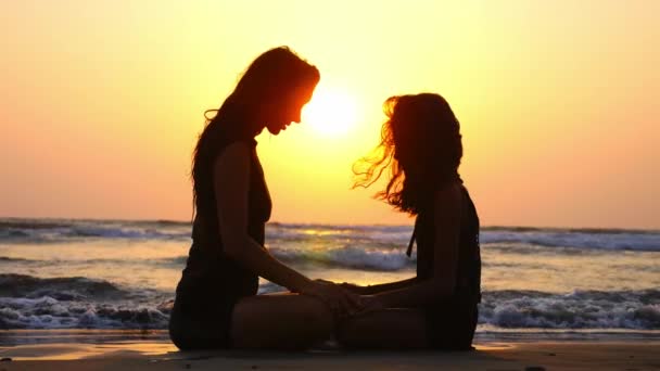 Мама и дочь медитируют вместе на берегу океана на прекрасном закате . — стоковое видео