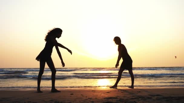 Silueta de jóvenes deportistas practicando elemento acrobático en la playa . — Vídeos de Stock