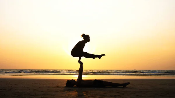 Подходящая спортивная пара практикует акро-йогу с партнером вместе на песчаном пляже . — стоковое фото