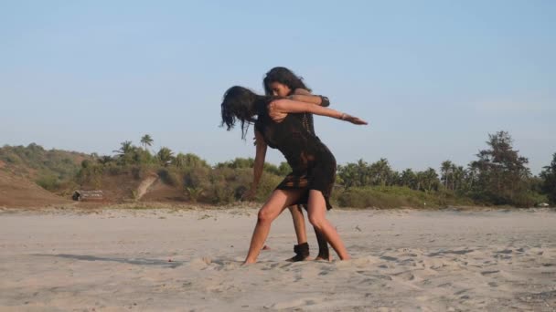 Mãe treina uma filha adolescente para executar elemento acrobático na praia — Vídeo de Stock