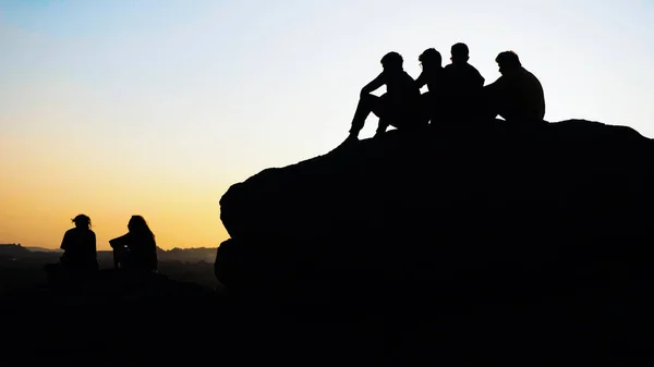 Grupo silhueta de pessoas admirando o pôr do sol no topo da montanha — Fotografia de Stock