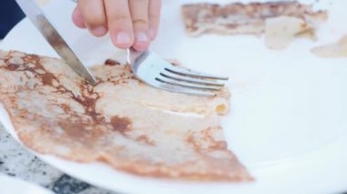 Küçük kız bir pancake kesme ve kahvaltı için yemek.