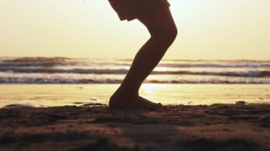Güneş batımında deniz kumu plajda ip atlama kız bacaklar silüeti.
