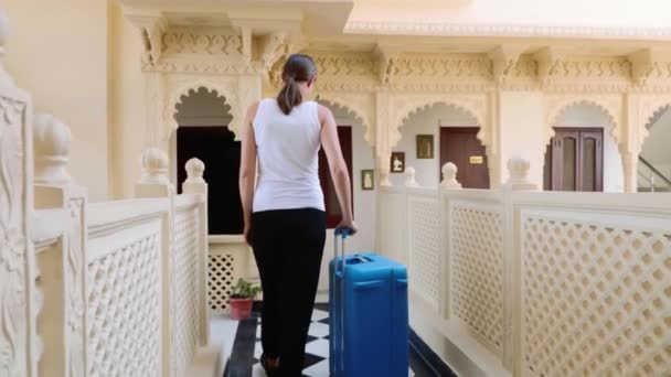 Женщина заселяется в отель и отвозит чемодан в свой номер. . — стоковое видео