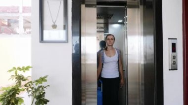 Bavullu ve sırt çantalı genç bir kadın otelden çıkarken asansörden çıkıyor..