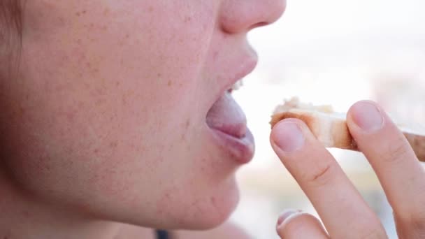 女性の口のクローズアップはトーストを噛み切って噛む、側面図. — ストック動画